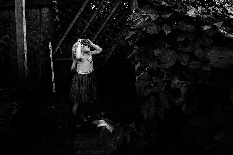 black and white picture. preschool girl takes picture of tree. 