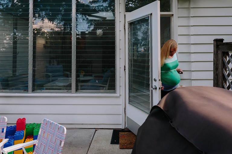 Pregnant mom walks out of patio door into backyard 