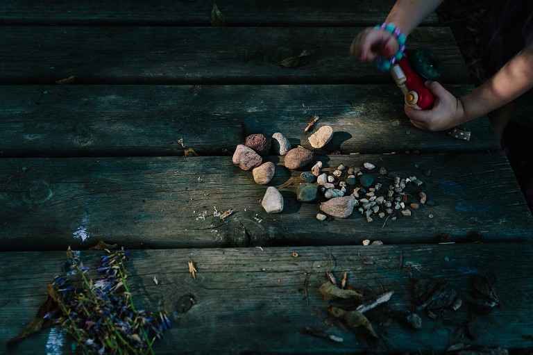 Child takes picture with toy camera of her rock collection. 