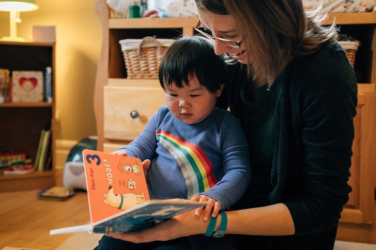 Mother reads with toddler daughter in daughter's bedroom. 
