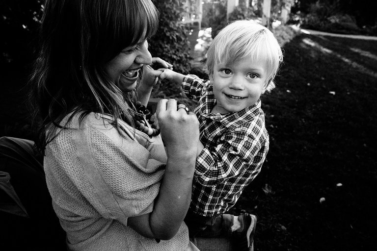 Young boy sits on his mother's lap and smiles. She smiles at him. Black and white. 