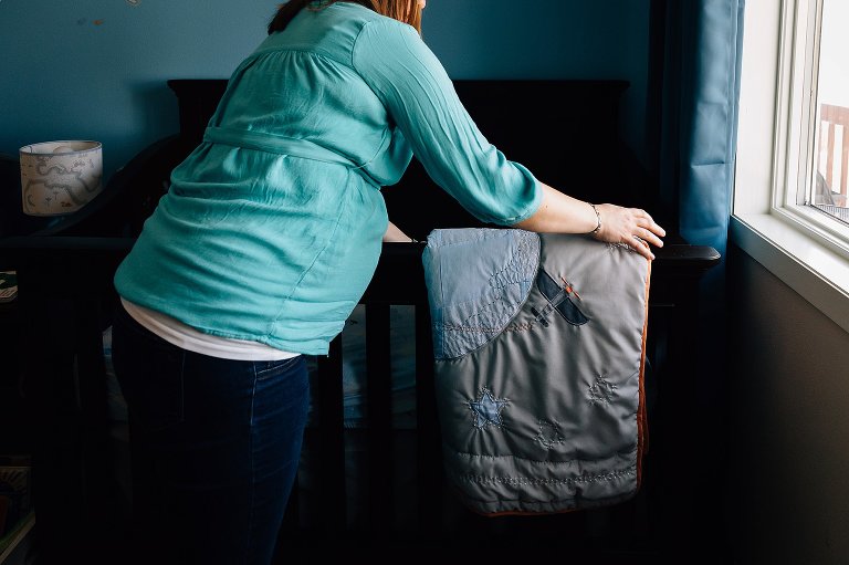Mother adds comforter to baby crib
