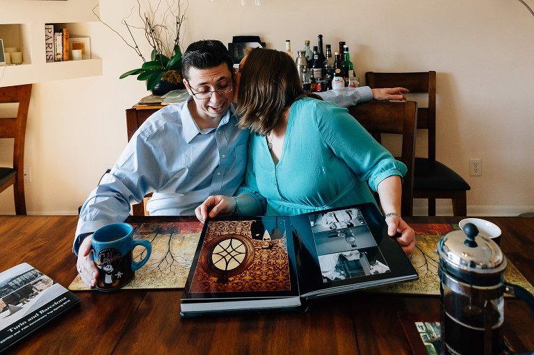 Expectant mother kisses father while looking at wedding pictures 