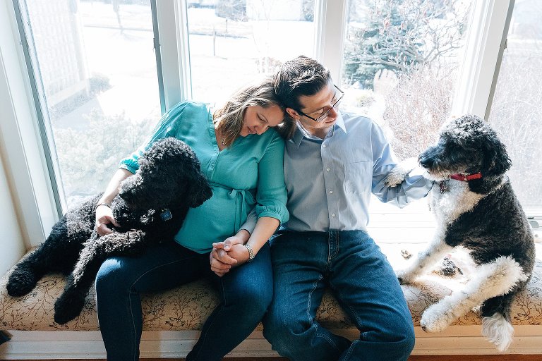 Expecting mother and father relax in sun with two dogs