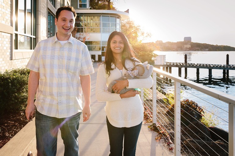 parents smile as they walk forward with and fall leaves behind them 