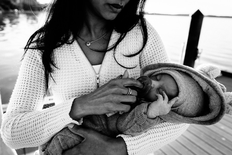 Mom holds pacifier in newborn's mouth 