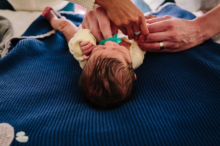 Two parents help change newborn's clothes at the same time