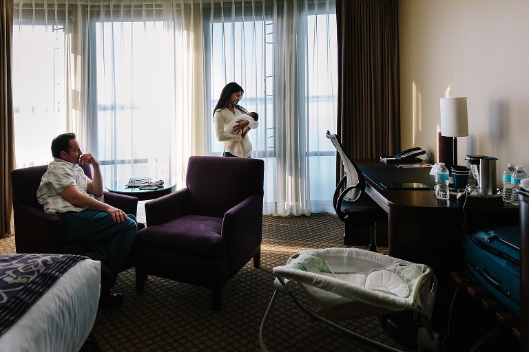 Parents are in hotel room on lake, holding newborn 