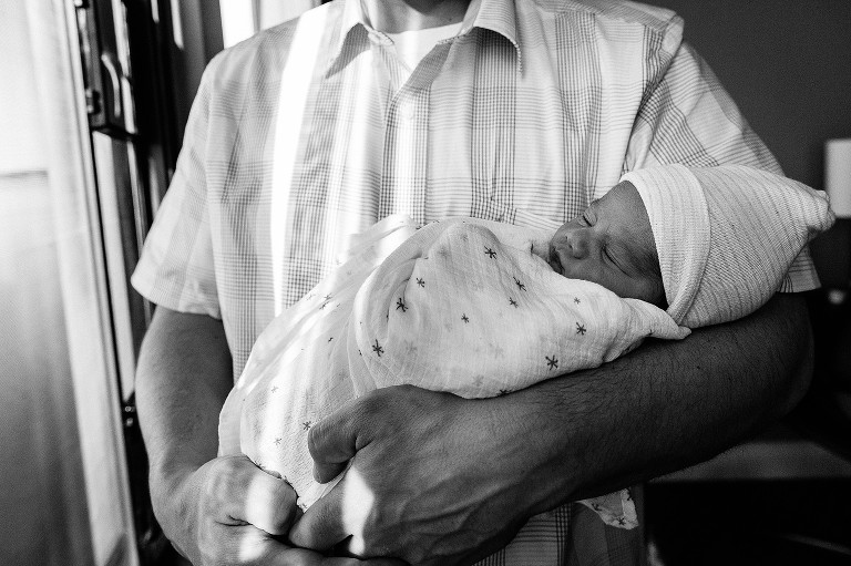 Newborn baby sleeps in dad's arms 