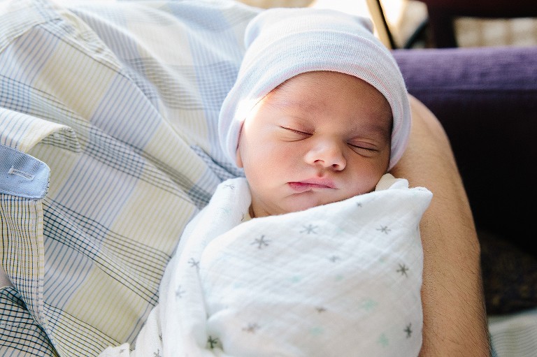 Newborn baby sleeps in dad's arms 