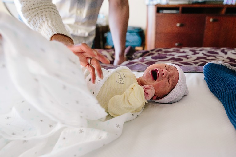 Newborn cries on bed 
