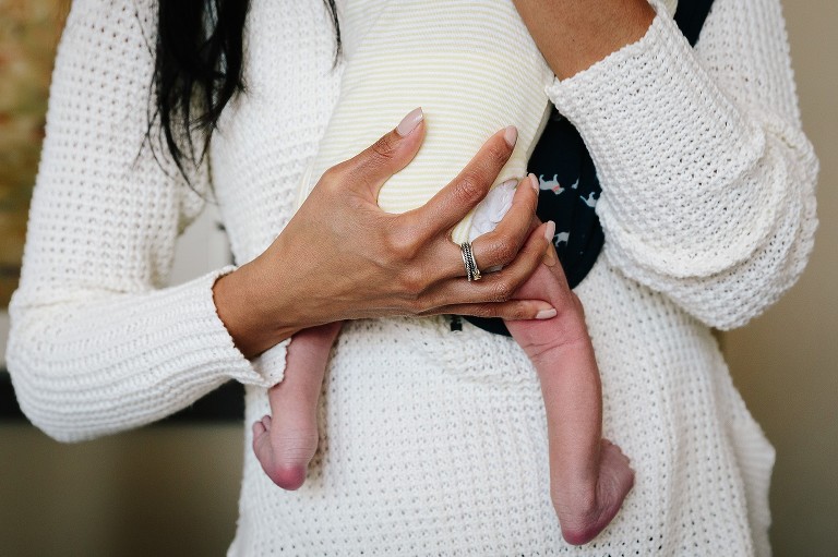 Mom's hands and tiny newborn leg details 