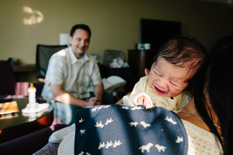 Baby cries and dad looks on