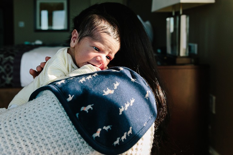 Mom burps newborn baby, baby has open eyes 