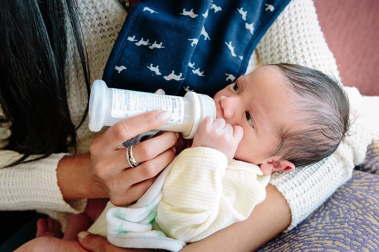 Mom holds newborn baby and gives him a bottle 