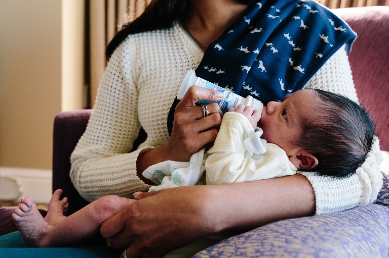 Mom holds newborn baby and gives him a bottle 
