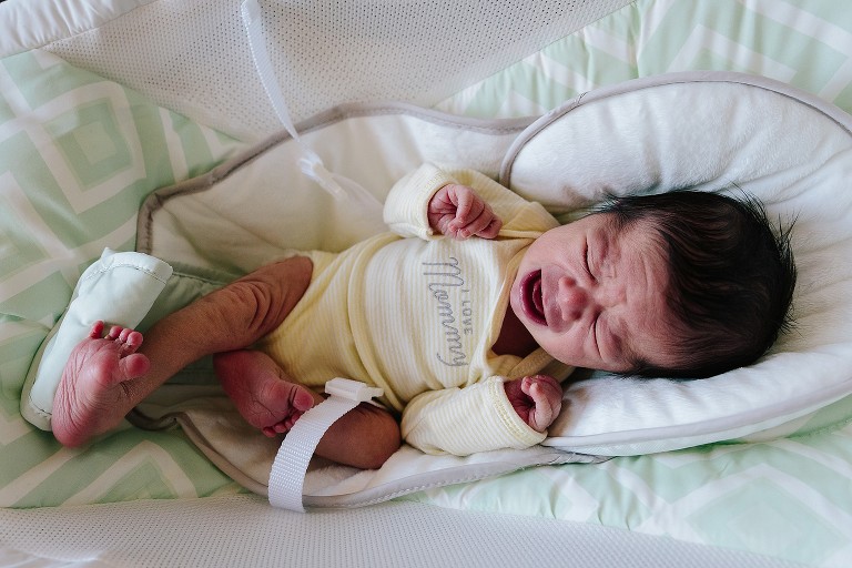 newborn stretches leg and cries 