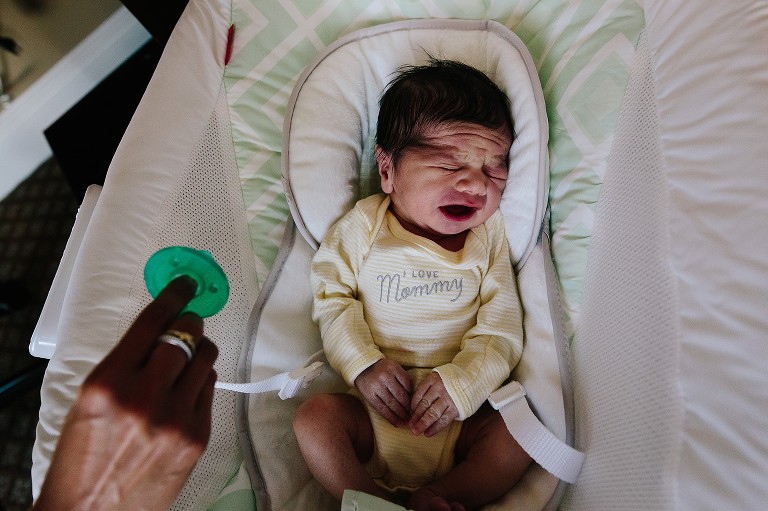 Newborn cries as mom comes in wiht pacifier 