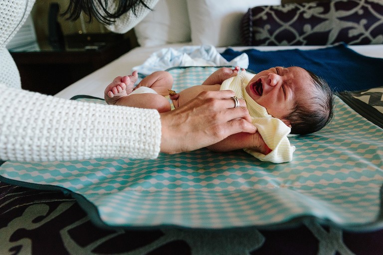 Newborn cries as mom changes his clothes 