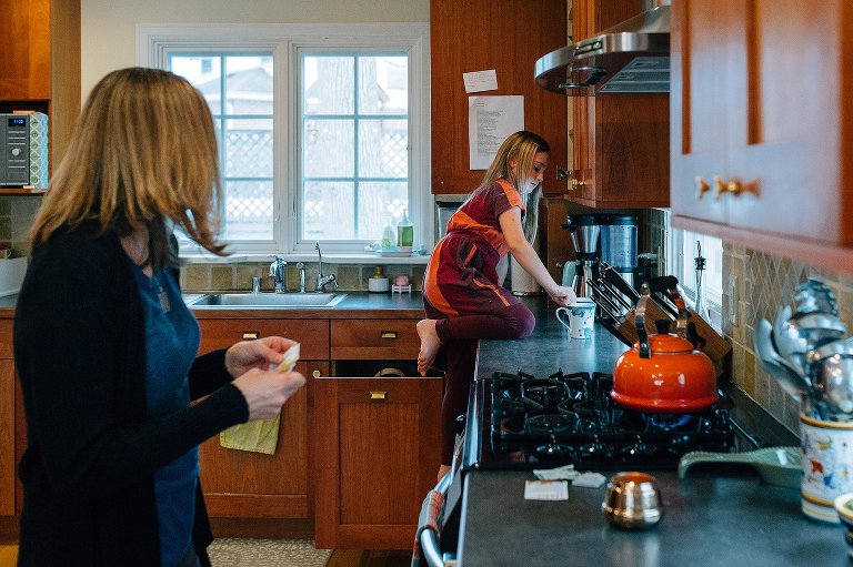 young girl climbs on kitchen counter to retrieve mug