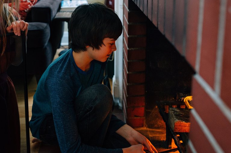 preteen boy stokes fire in fireplace 