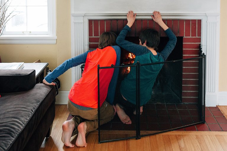 Brothers work on building a fire in the fireplace 