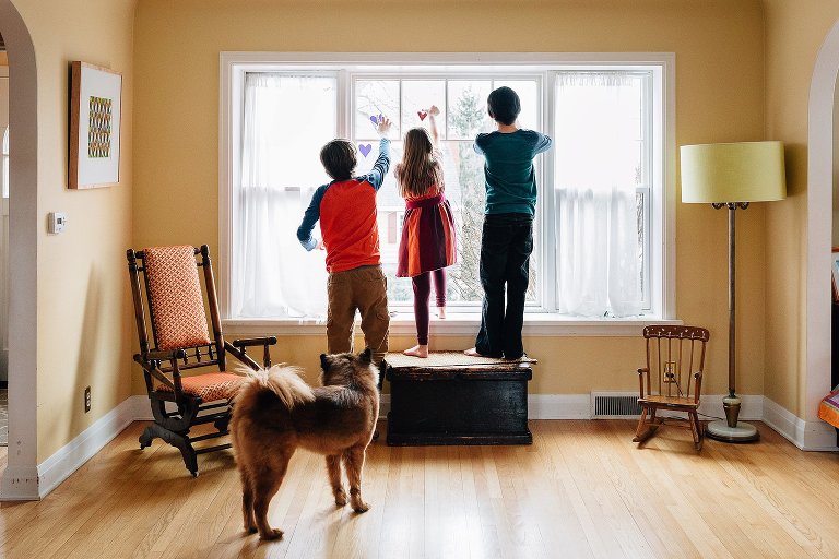 All three kids tape construction hearts to the window 