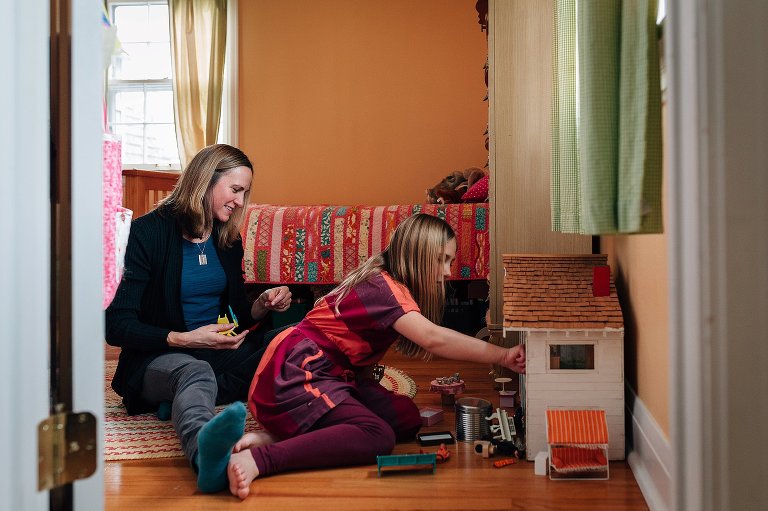 Mom and daughter play with dollhouse together 