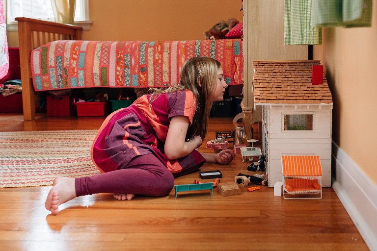 young girl plays with dollhouse 