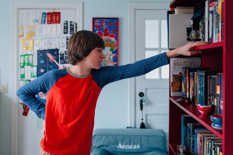Teen boys looks at books in his room