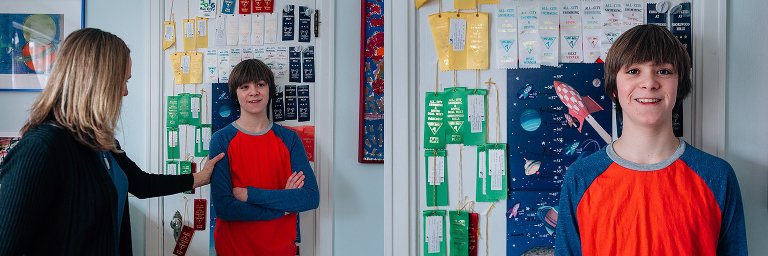 Teen boys shows off swimming ribbons and growth chart