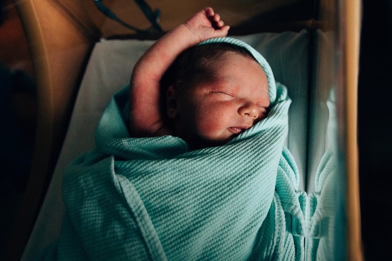 Sleeping baby in hospital blanket and bassinet 