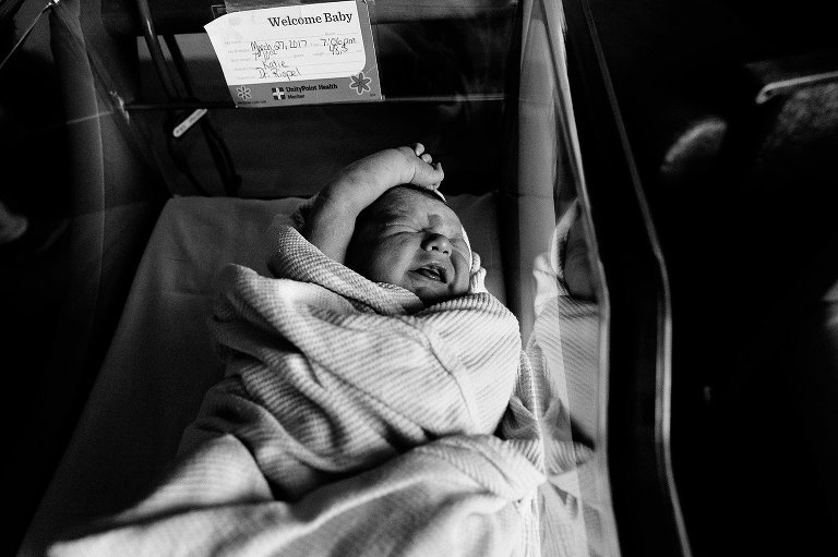 Black and white image of baby stretching and about to cry.