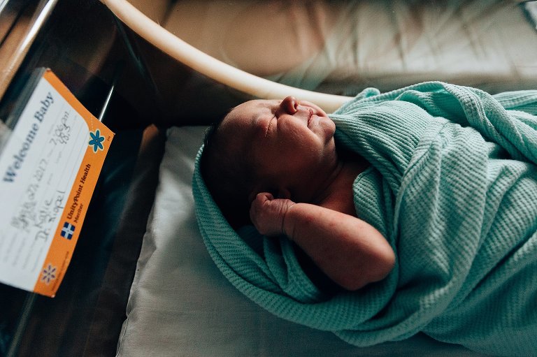 Newborn sleeps in hospital bassinet 
