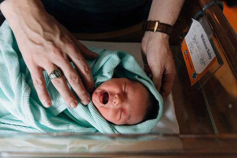Newborn yawns in hospital basinet 