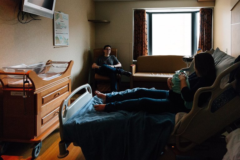 Mom in hospital bed, Dad watching Mom and baby