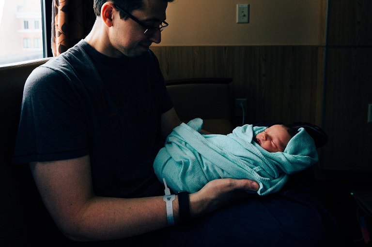 New dad holding baby in hospital room