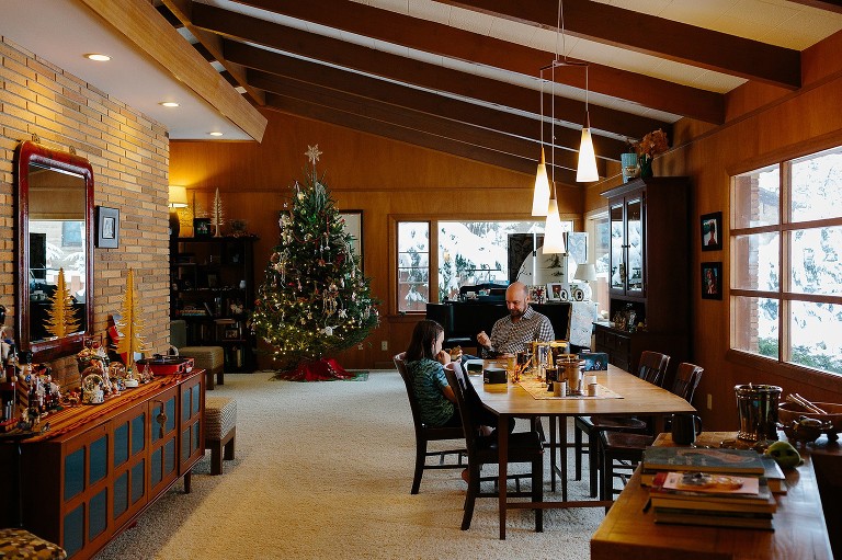 Dad and son play cards. Snowy day and Christmas tree is lit. 