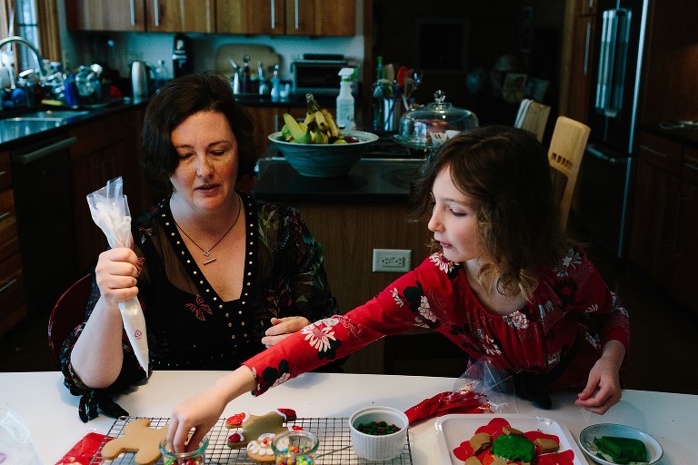 Mother and daughter work on decorating gingerbread men in kitchen