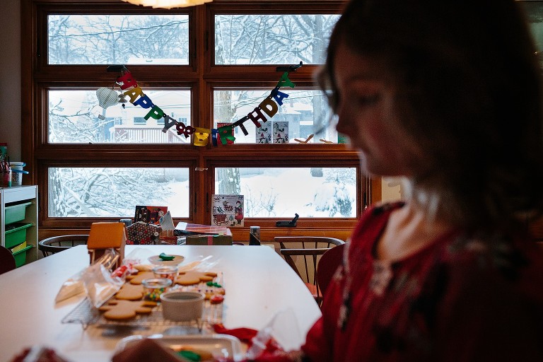 Sign in background says, Happy Birthday. Girl in foreground making gingerbread cookies