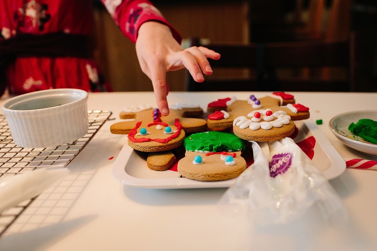 Girl places final decoration on gingerbread cookie. 