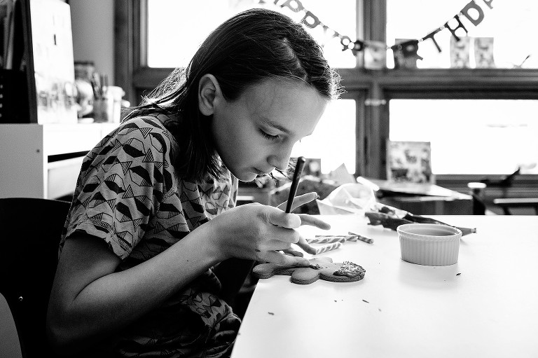 Preteen boys works carefully on decorating gingerbread boy