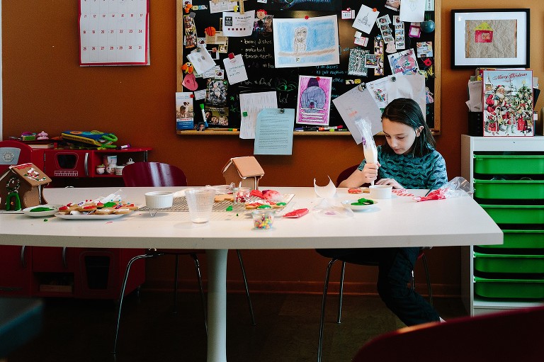 Boy sits alone at kitchen table full of decorating materials to make gingerbread boy