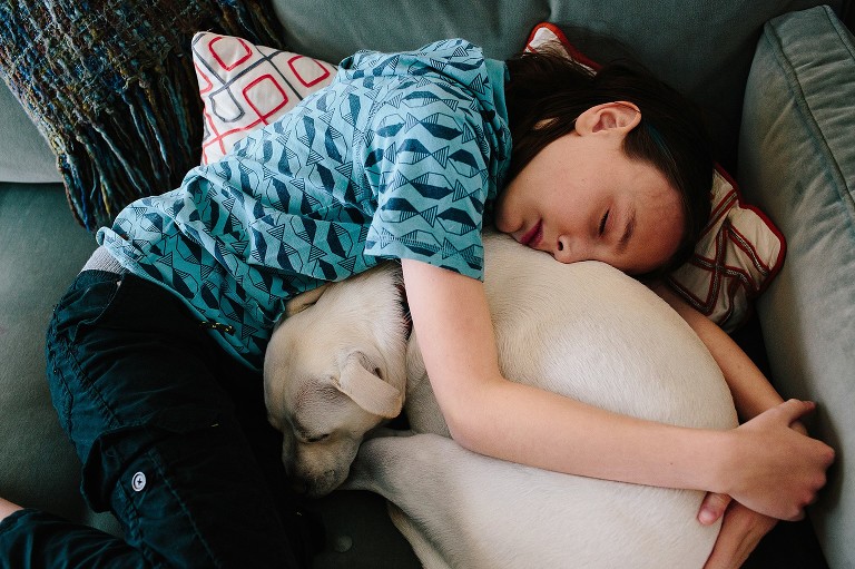 Boy sleeps with this curled up dog. 