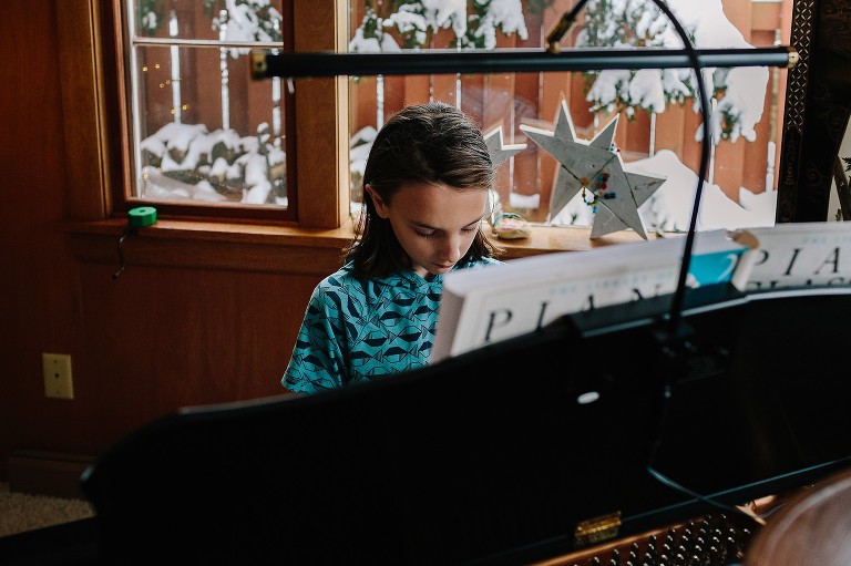 Boy plays piano, snow outside 
