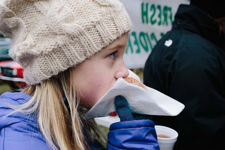 Girl eats donut, wearing winter hat and mittens