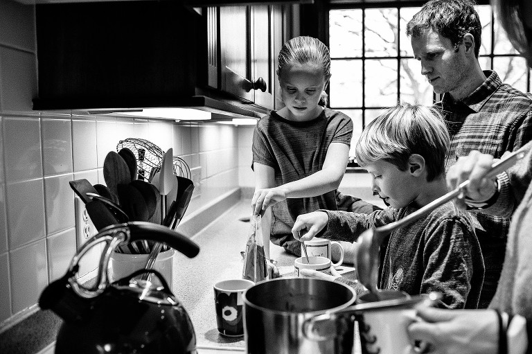 Girl and boy stir hot chocolate while Mom ladles more hot chocolate into mugs. 