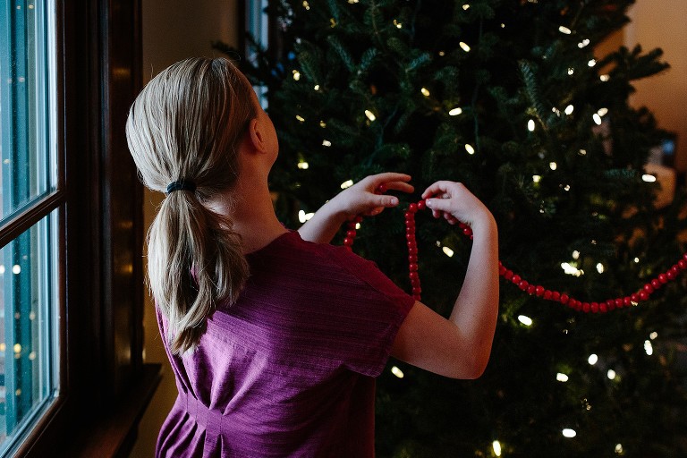 Girl decorates Christmas tree in living room