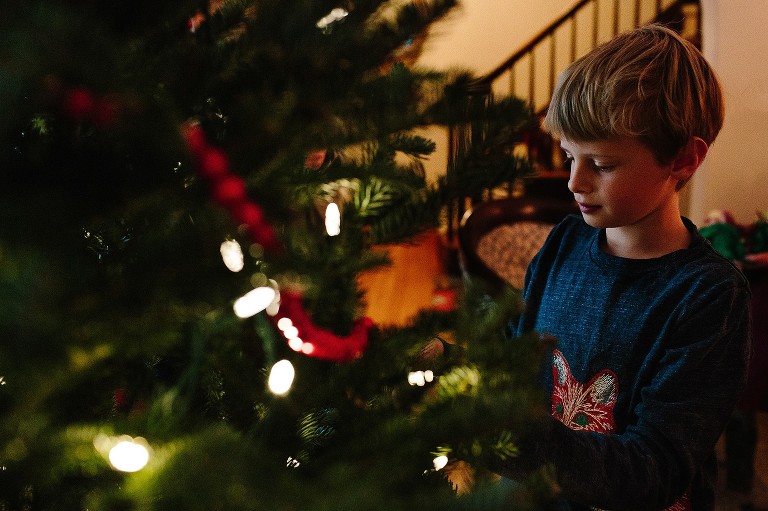 Boy decorates Christmas tree in living room