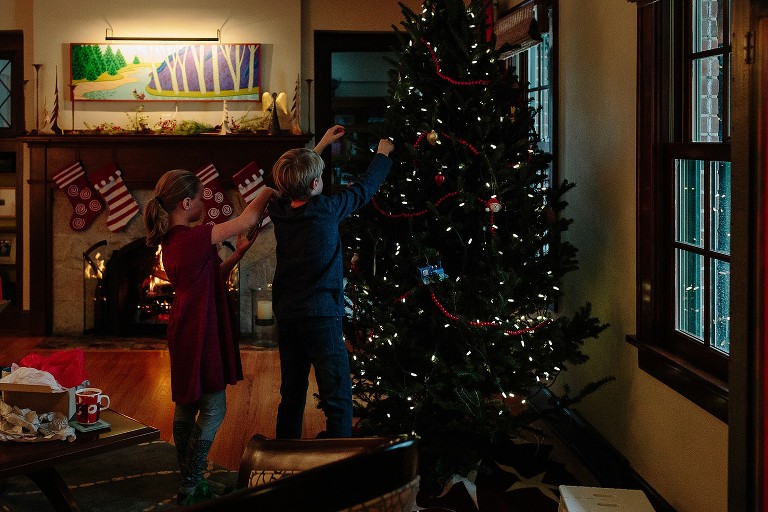 Children decorate Christmas tree in living room